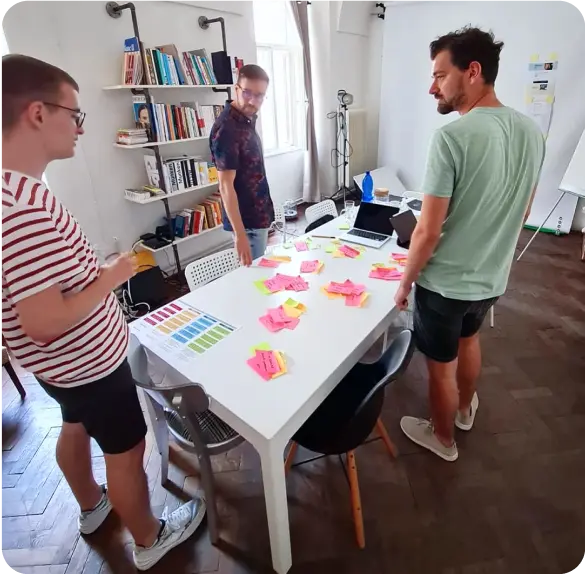 A workshop in the studio: three people around a table covered in sticky notes