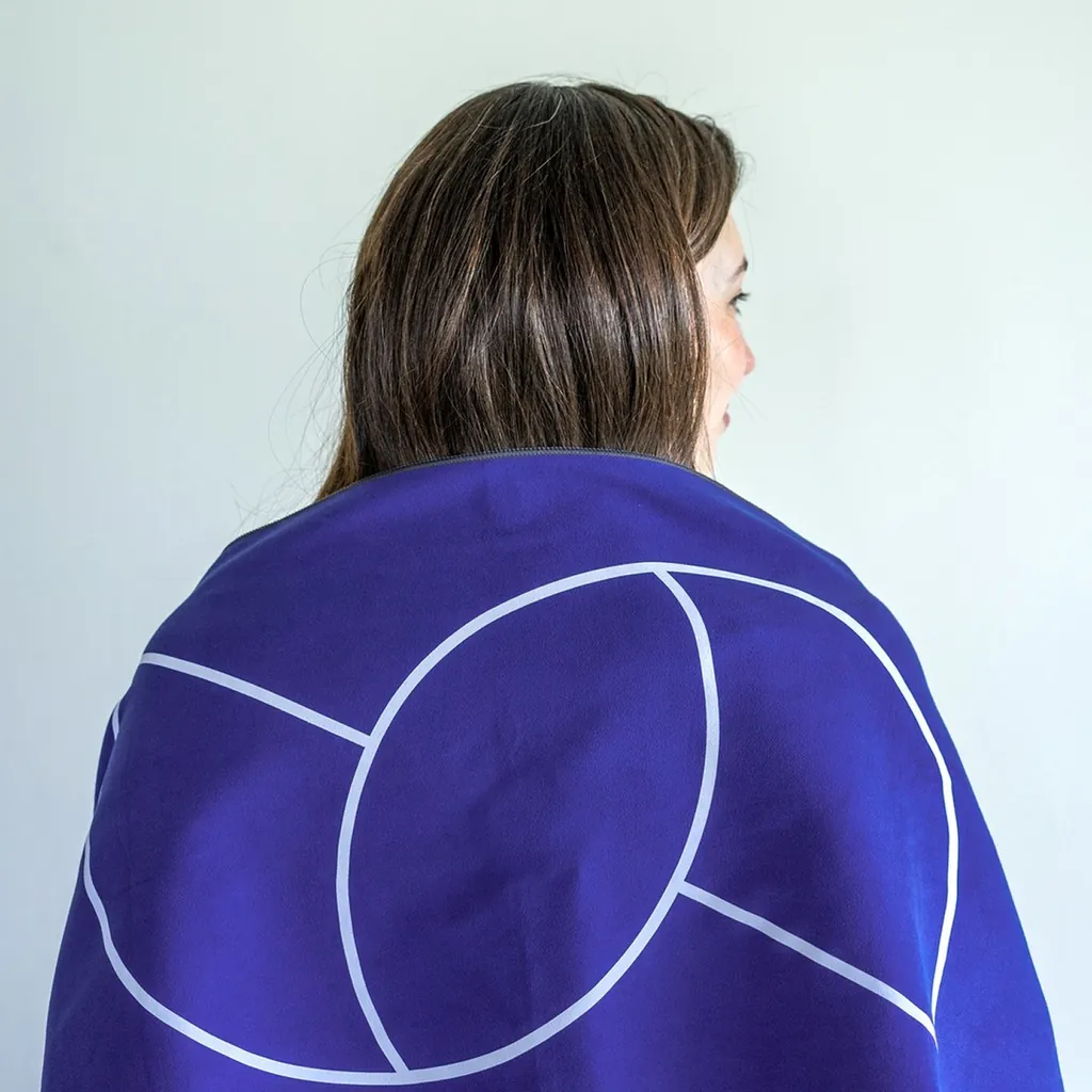A person wrapped in a purple Sudolabs blanket with the S line pattern