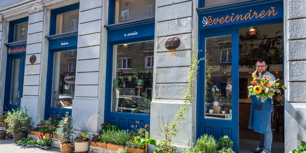 The Kvetináreň shop front in Bratislava with its sign, a man holding a bouquet in the doorway