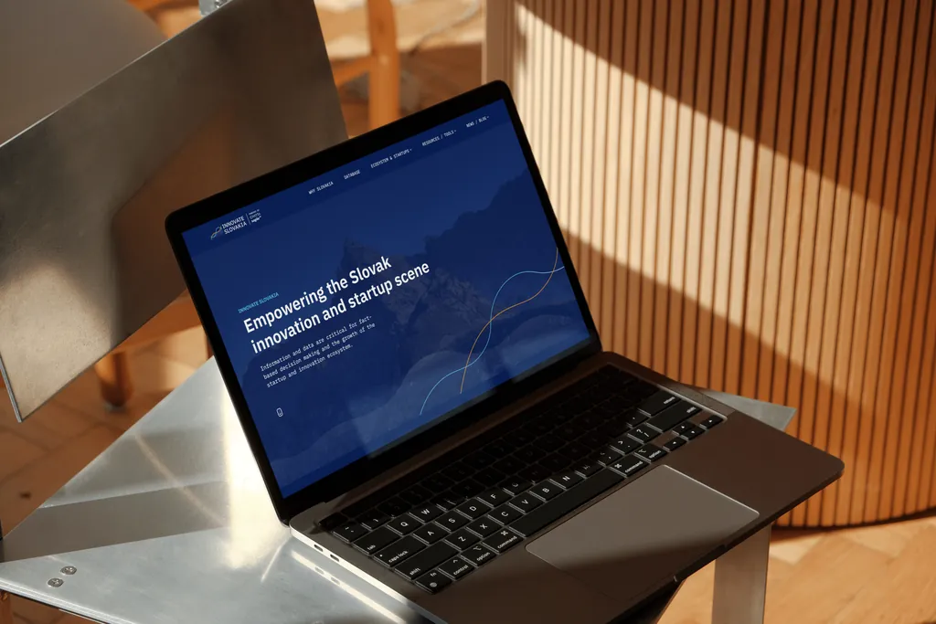 The Innovate Slovakia homepage, “Empowering the Slovak innovation and startup scene”, on a laptop resting on a metal chair
