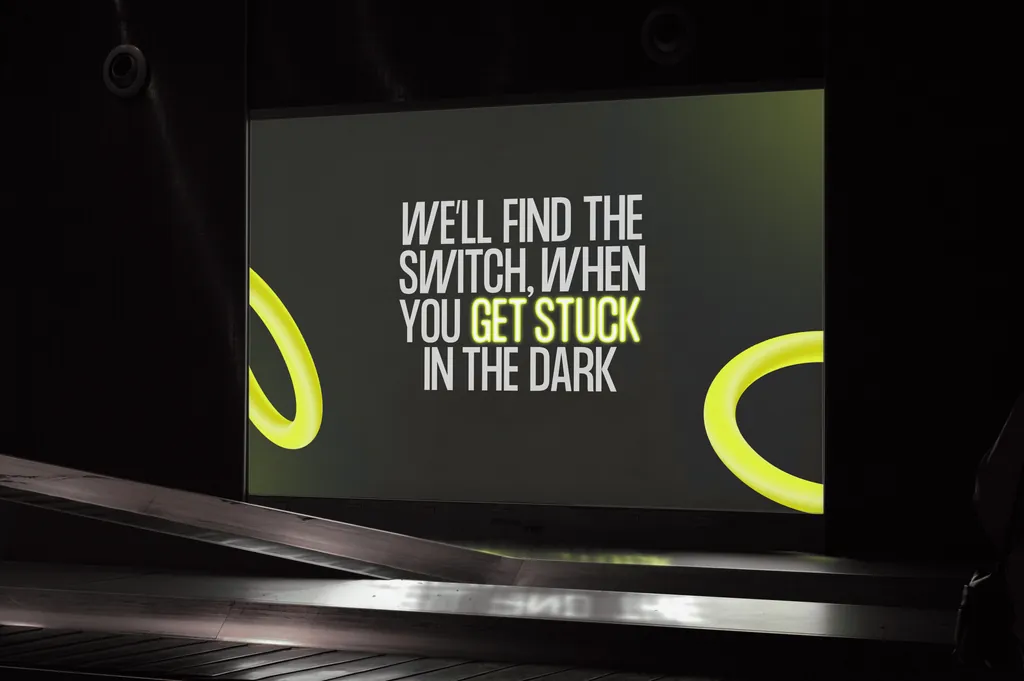 A Challenger slide on a stage screen: “We'll find the switch when you get stuck in the dark”, with the yellow loop
